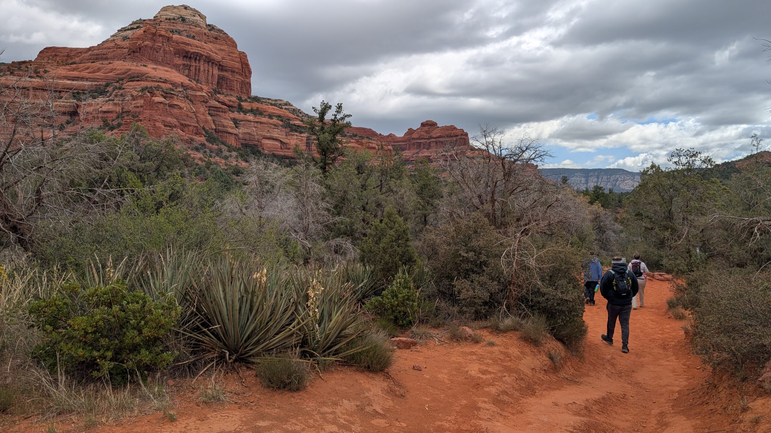 People hiking on a trail with red rocks in the background