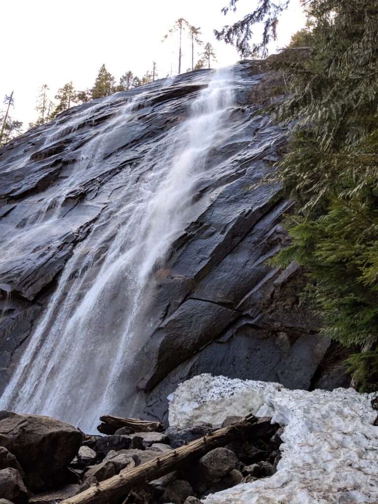 Waterfall running down large black rock cliff